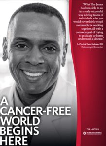 Black-and-white portrait of a smiling man beside a red panel featuring the phrase 'A cancer-free world begins here'—a cancer-awareness campaign banner. | Jerad Schutt | Nashville Marketing Consultant | Fractional CMO | Jerad Schutt | Nashville Marketing Consultant | Fractional CMO