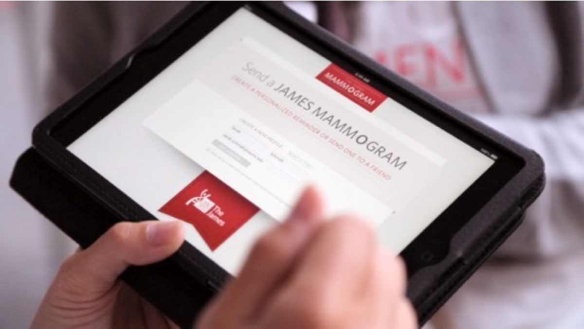 Hand holding a tablet that displays a 'Send a Mammogram' submission form with a red logo on screen. | Jerad Schutt | Nashville Marketing Consultant | Fractional CMO | Jerad Schutt | Nashville Marketing Consultant | Fractional CMO