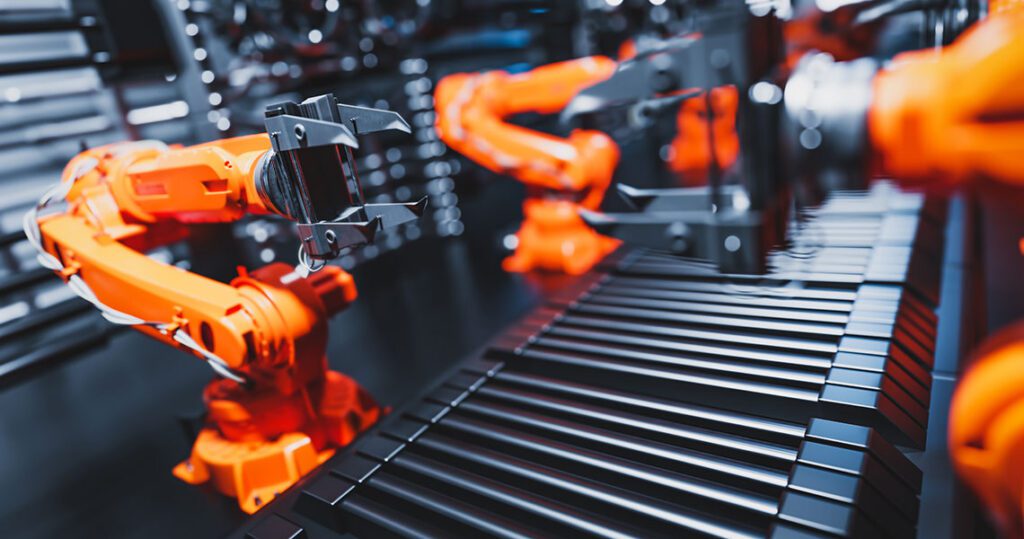 Orange robotic arms at a production line assembling parts on a conveyor belt in a high-tech factory environment, emphasizing automation. | Jerad Schutt | Nashville Marketing Consultant | Fractional CMO | Jerad Schutt | Nashville Marketing Consultant | Fractional CMO