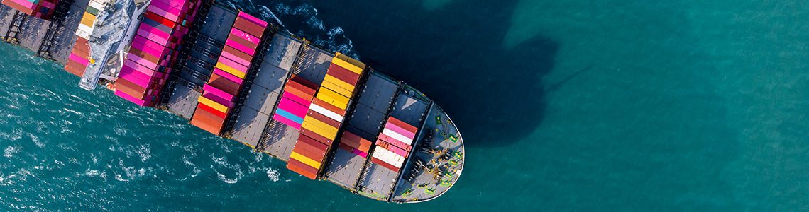 A top-down view of a large cargo ship sailing through turquoise water, stacked with colorful shipping containers. | Jerad Schutt | Nashville Marketing Consultant | Fractional CMO | Jerad Schutt | Nashville Marketing Consultant | Fractional CMO
